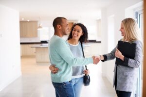 First-time buyers shaking hands with real estate agent in new home