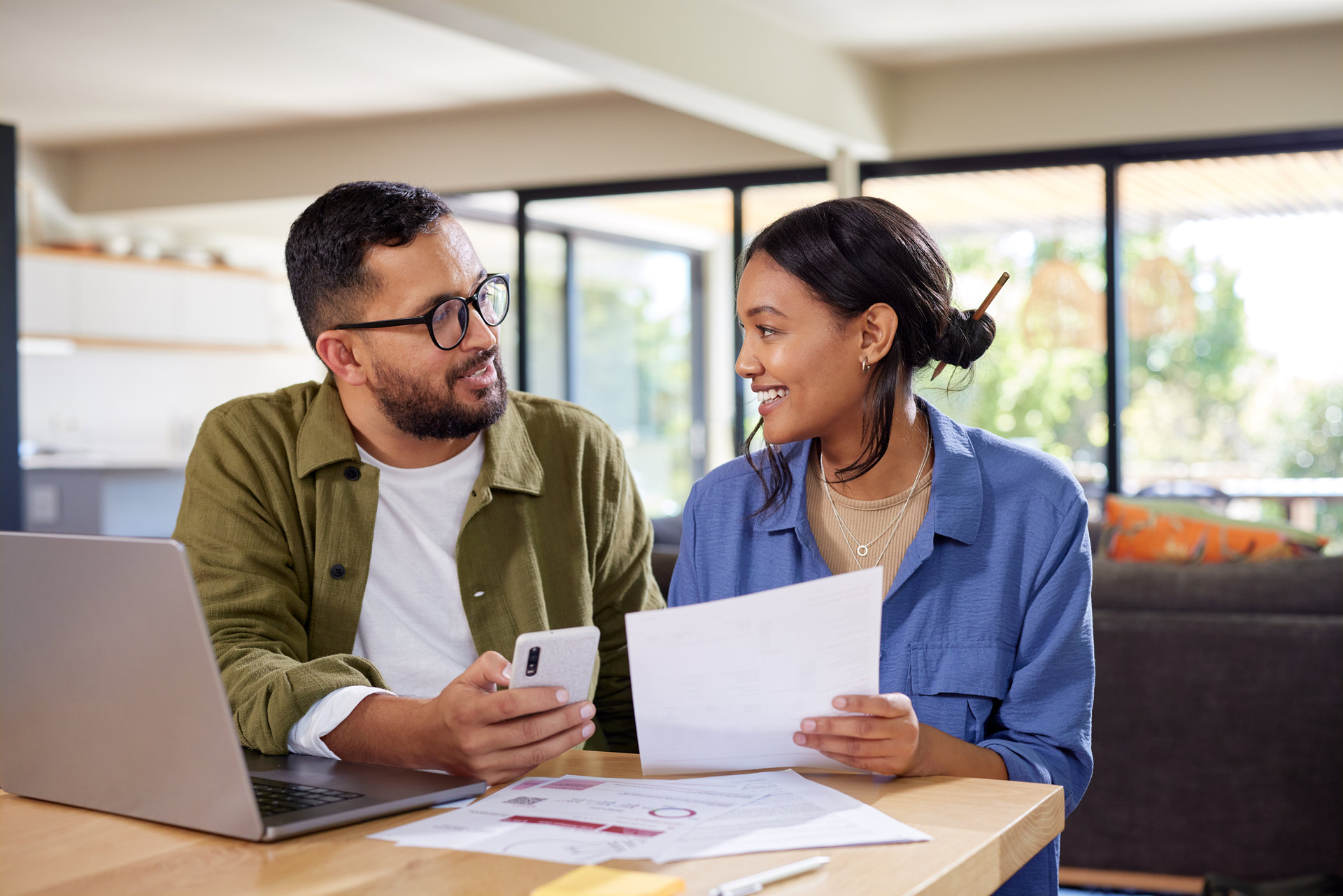 smiling-couple-discussing-finances-at-wooden-table
